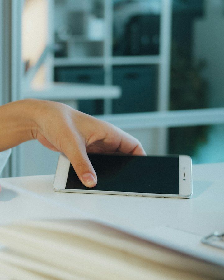 Hand placing a smartphone on an office desk