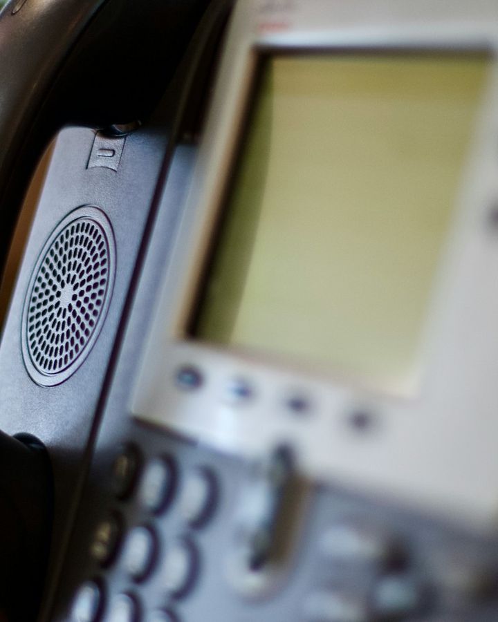 Close-up of an IP phone display with a headset beside it