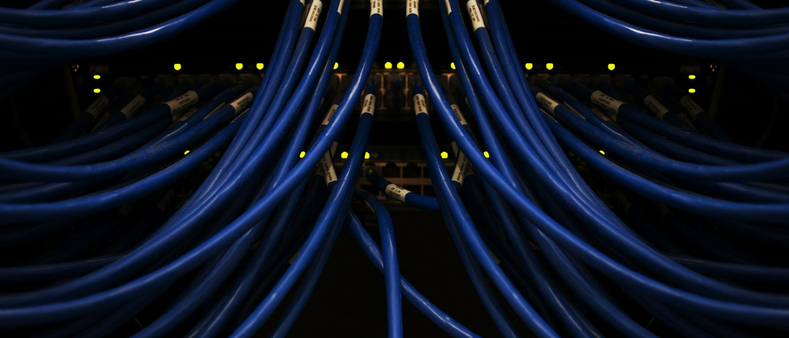 Rows of network cables plugged into switches in a dark rack
