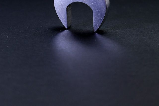 Steel spanner standing on its jaw on a dark surface