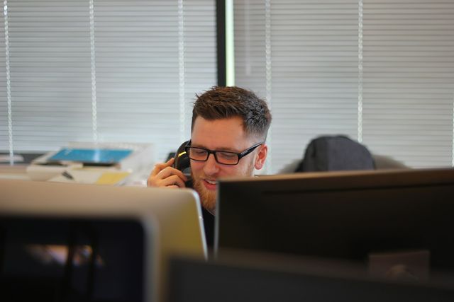 Support engineer on a desk phone call behind his monitors