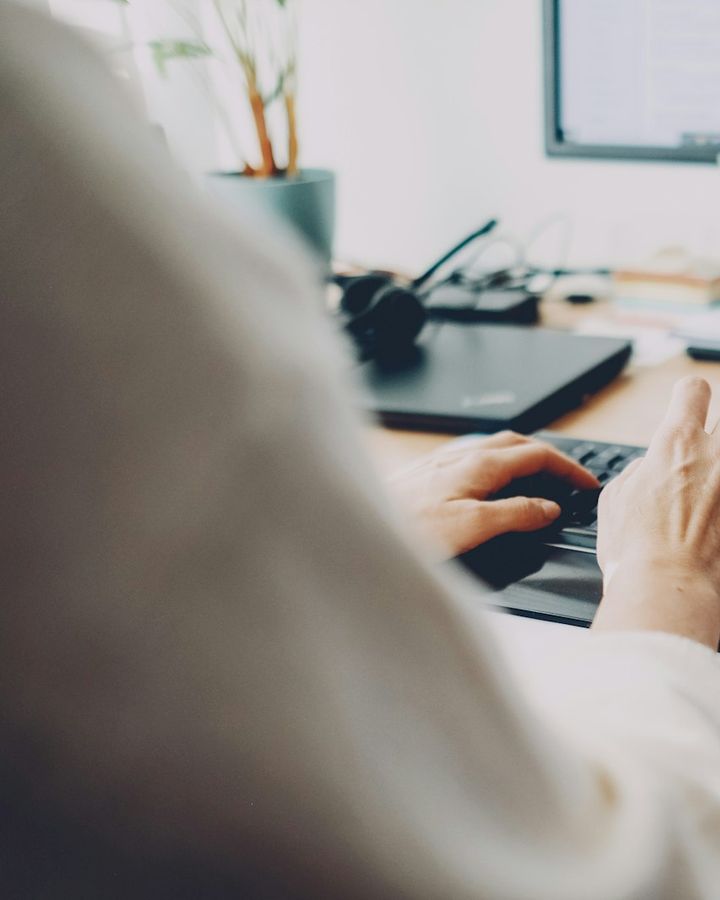 Hands typing at a desk with two monitors