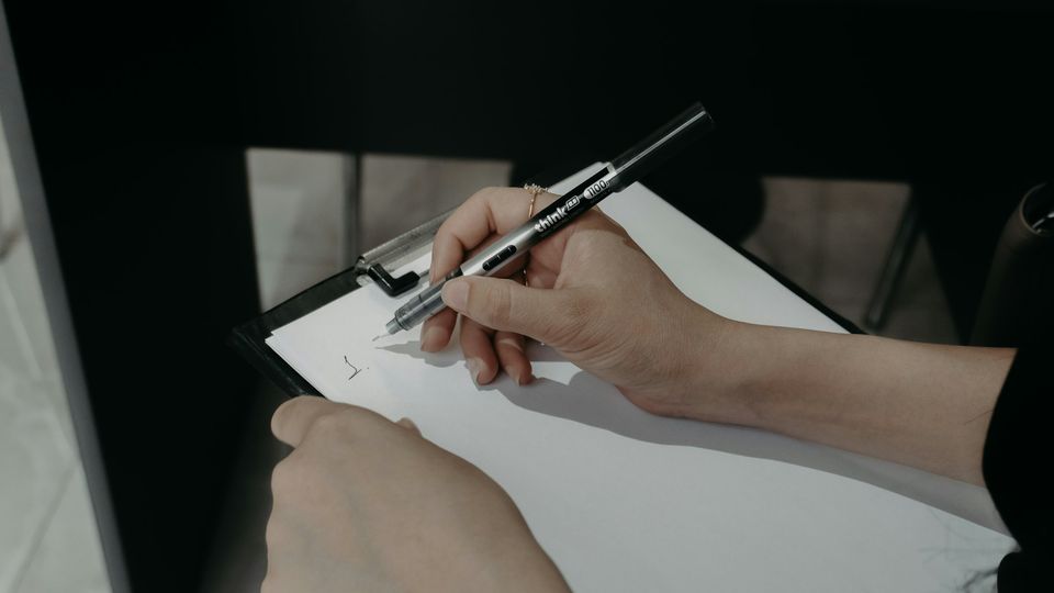 Hands writing on a clipboard with a pen during an assessment