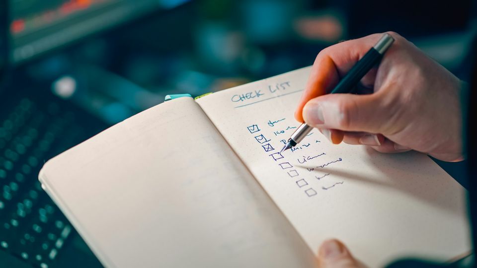 Hand ticking items off a handwritten checklist